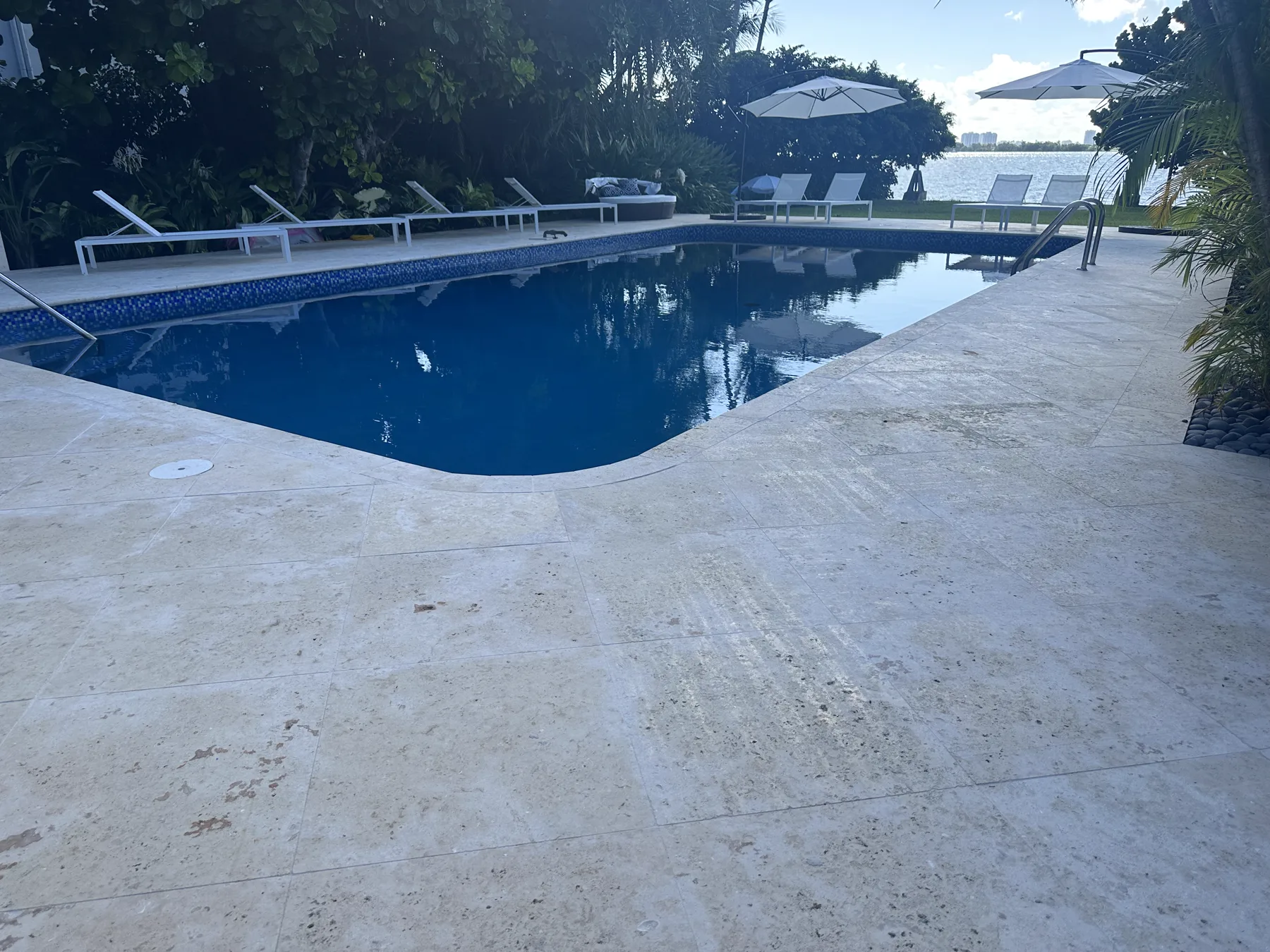 Finished 12x24 coral stone surrounding a filled waterfront pool in Miami Beach