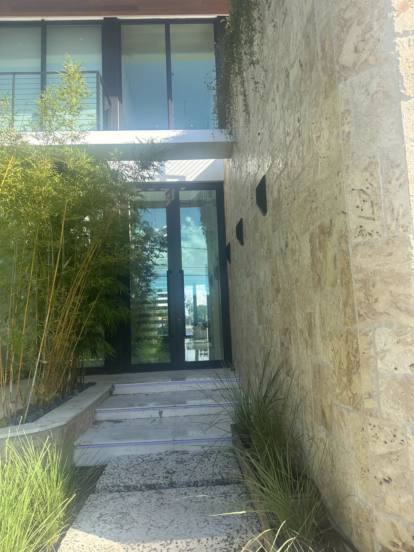 Oolite stone entry wall and glass entrance at a modern Miami Beach residence