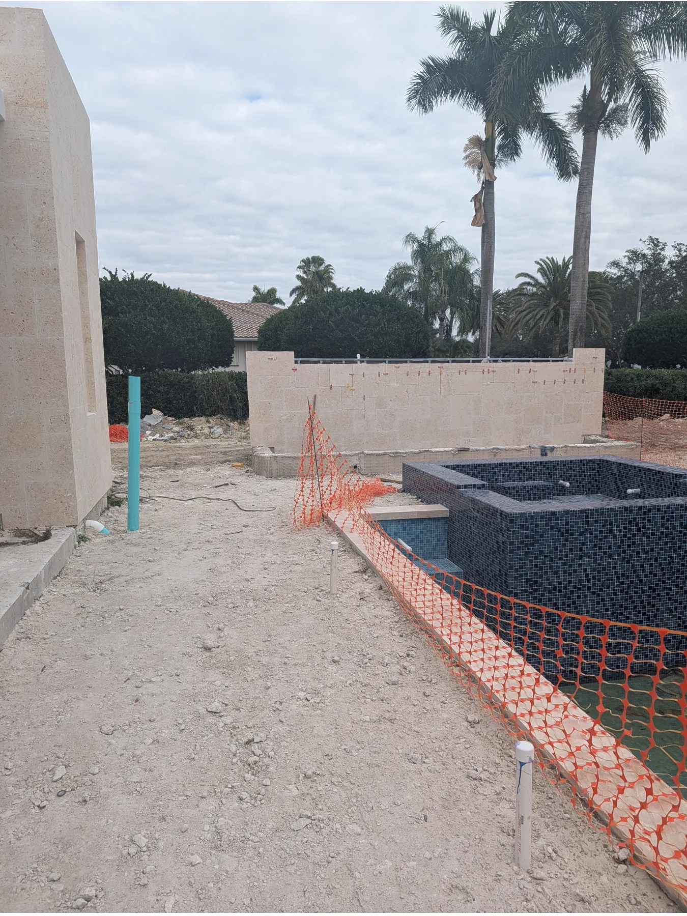 Tall coral stone wall beside the pool construction area in Pinecrest