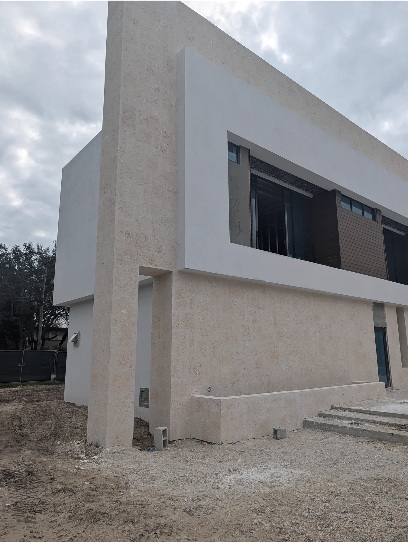 Long side elevation clad in coral stone at a modern Pinecrest home