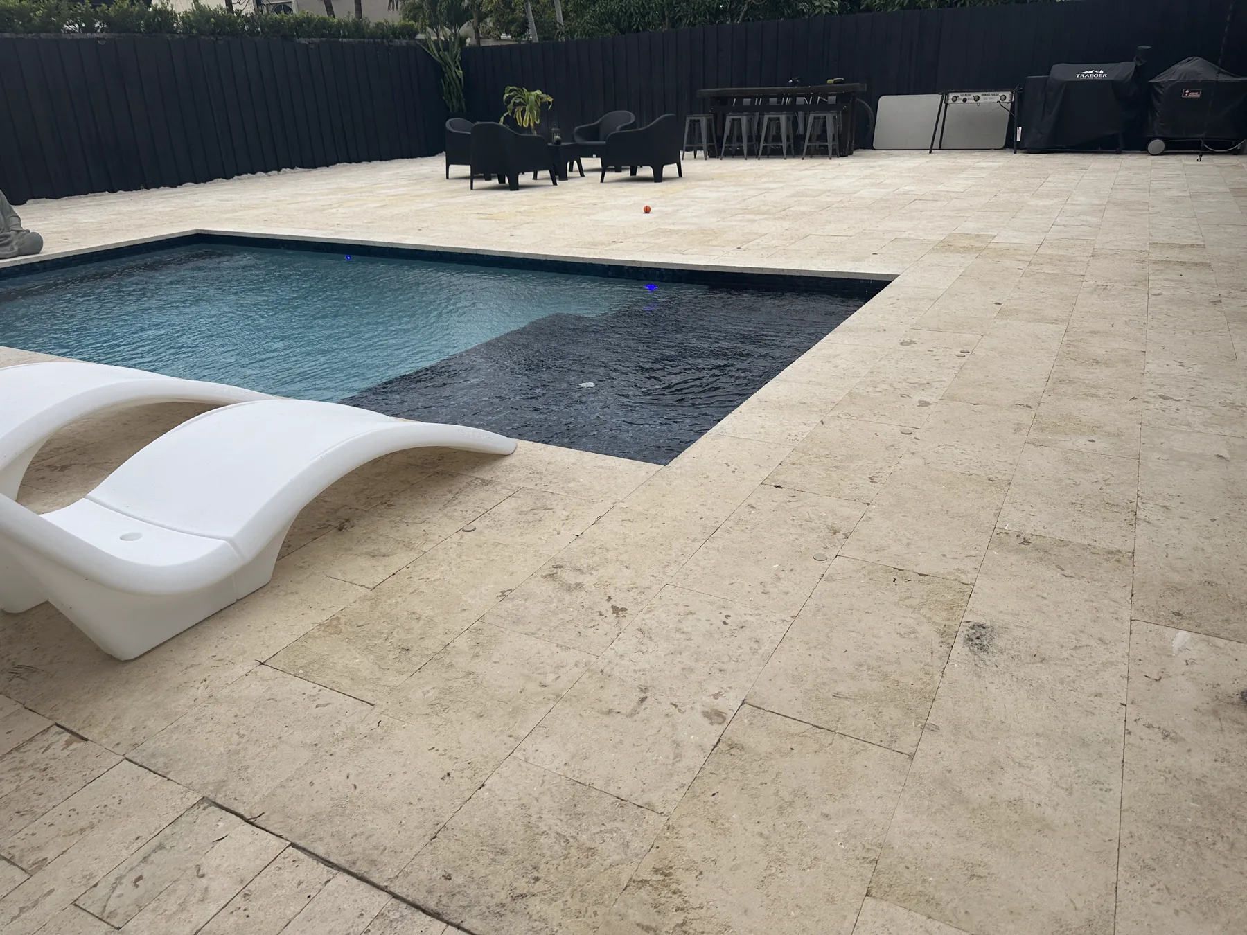 Coral stone pavers surrounding the dark-finish residential pool