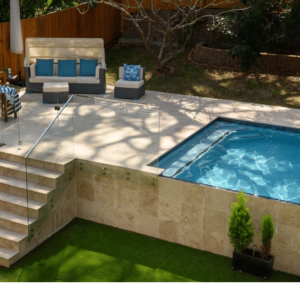 Above-ground pool with luxurious coral stone decking.