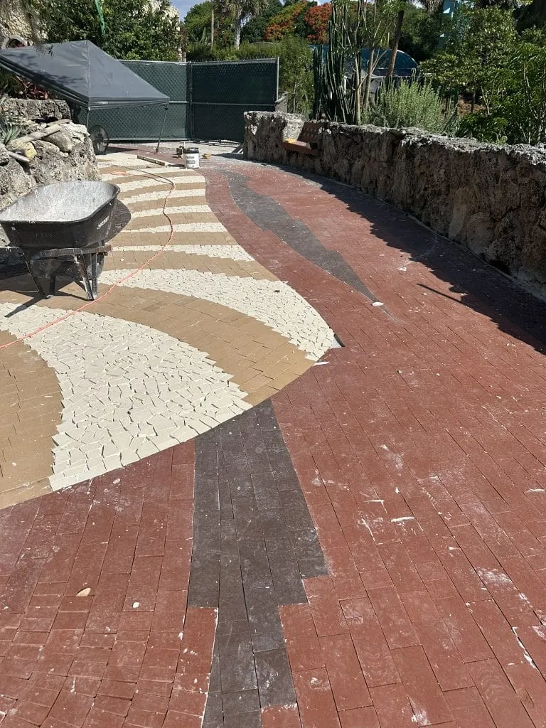 Pinecrest Gardens Park restoration in Miami featuring artistic red, beige, and brown pavers arranged in a curved mosaic walkway design.