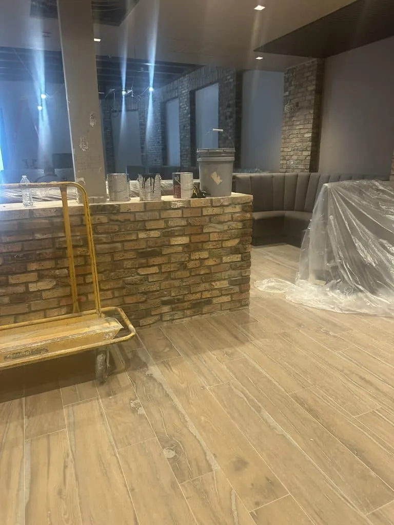 Interior commercial installation featuring wood-look tile flooring and rustic brick paver veneer on a counter/bar.