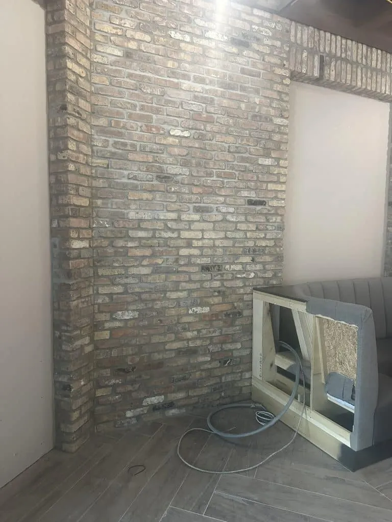 Finished interior brick feature wall and column masonry alongside herringbone wood-look tile installation. High-end paver and tile installation services in Miami-Dade County.