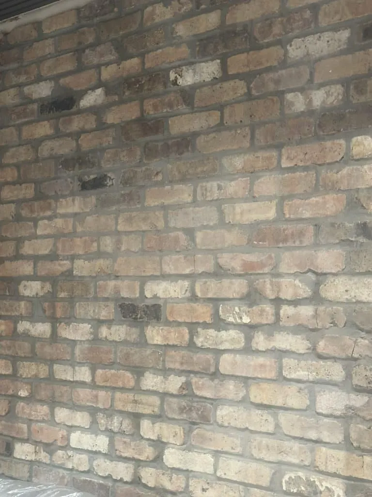 Rustic brick wall veneer installation in Miami area. Textured masonry work featuring natural, multi-color decorative bricks and mortar for an interior feature wall.